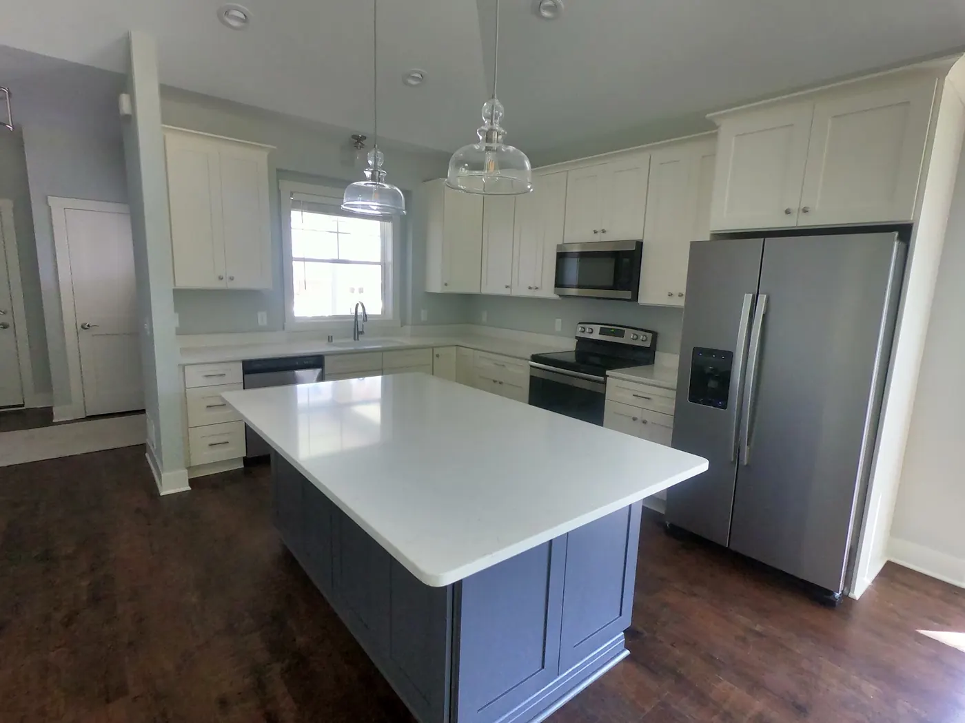 Kitchen with white painted cabinets and a navy island under white quartz