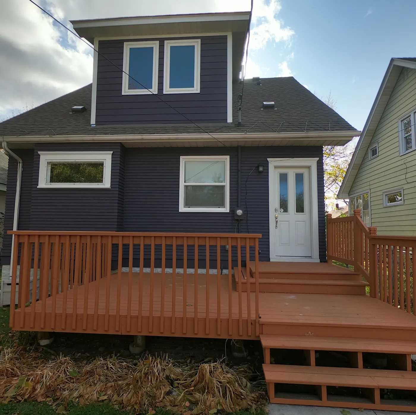Navy house with a freshly stained deck, painted by Villa's Pro Painting